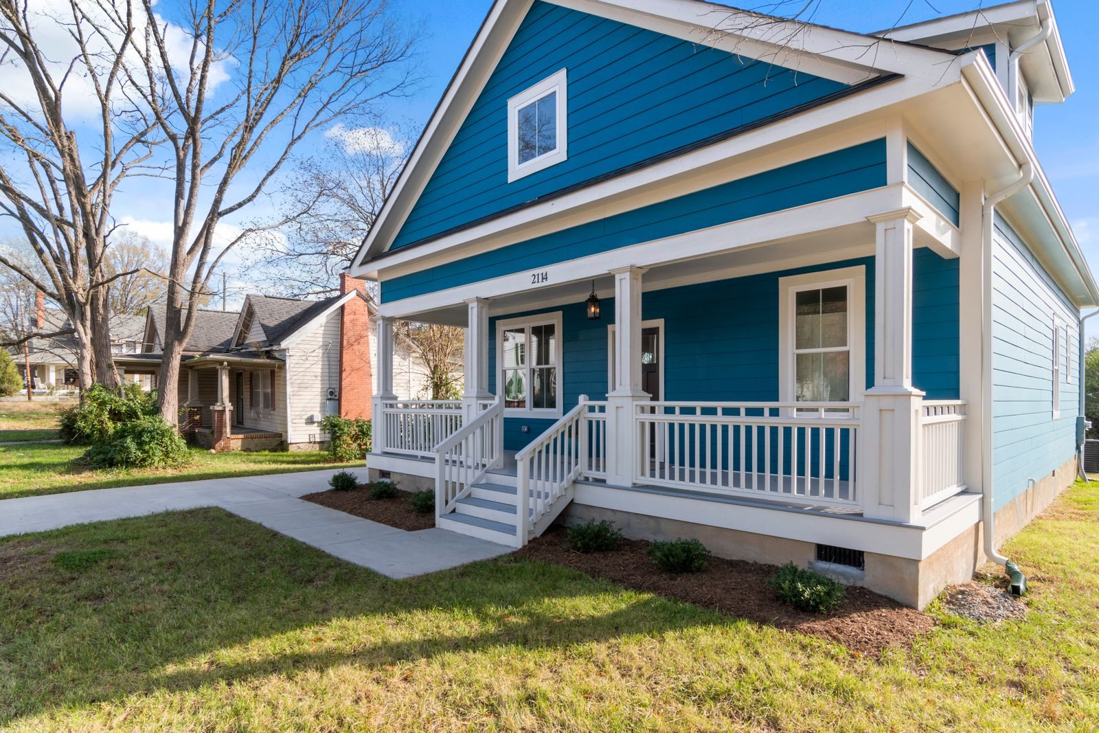 A blue house with a white front porch on a sunny day